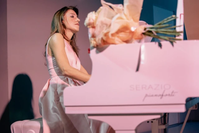 Giulia Vazzoler playing a pink-lit Serazio grand piano, roses on the lid