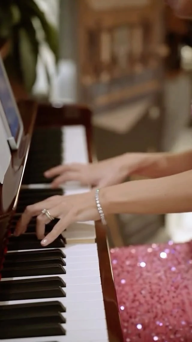 Hands on a piano keyboard beside a sequinned dress