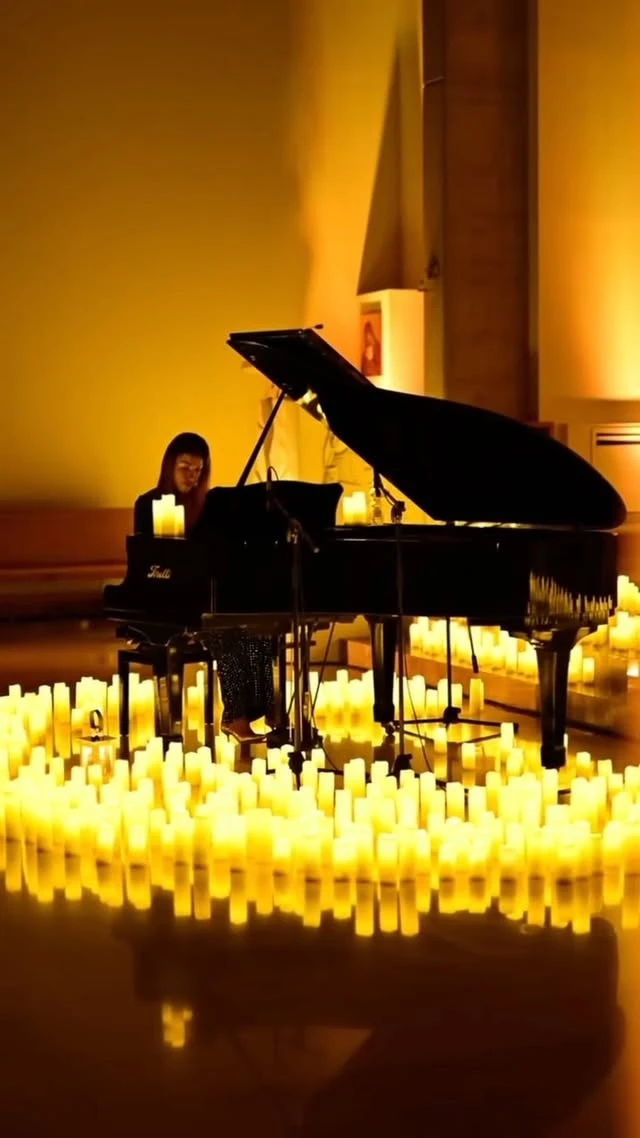 A grand piano in a dark room surrounded by hundreds of candles